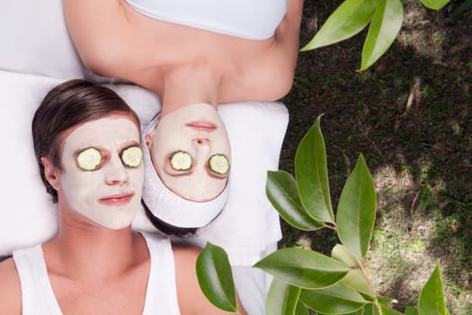 Couple with face pack and cucumber slices on their eyes