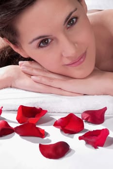 Portrait of a woman lying on a massage table with rose petals