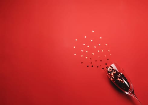 Valentine with wine glass, heart glitter on red background. High quality photo