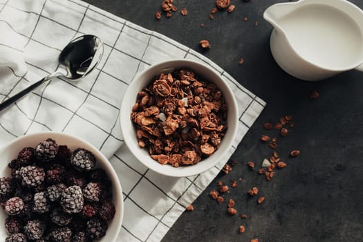 Frozen blackberries, granola, cream, towel on table. Blurred background. High quality photo