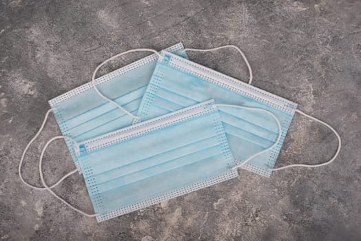 Surgeon masks to protect from Covid-19, worldwide pandemic in 2020 and 2021, blue coloured, empty copy space for text, isolated on a textured background