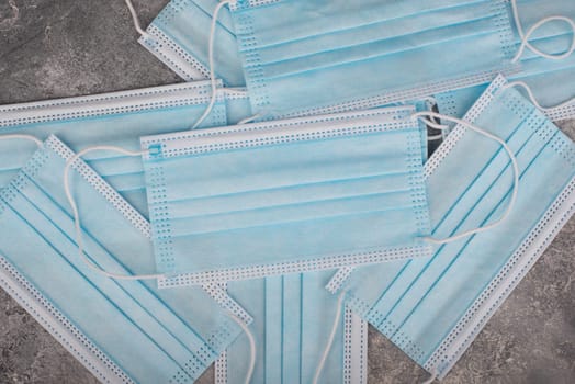 Surgeon masks to protect from Covid-19, worldwide pandemic in 2020 and 2021, blue coloured, empty copy space for text, isolated on a textured background