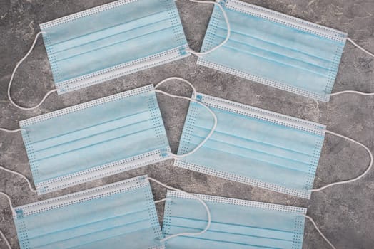 Surgeon masks to protect from Covid-19, worldwide pandemic in 2020 and 2021, blue coloured, empty copy space for text, isolated on a textured background