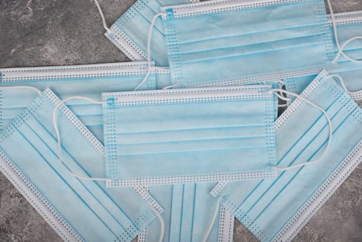 Surgeon masks to protect from Covid-19, worldwide pandemic in 2020 and 2021, blue coloured, empty copy space for text, isolated on a textured background