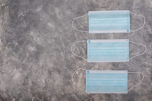 Surgeon masks to protect from Covid-19, worldwide pandemic in 2020 and 2021, blue coloured, empty copy space for text, isolated on a textured background
