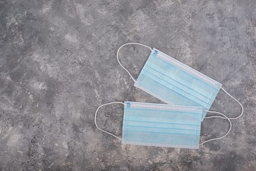 Surgeon masks to protect from Covid-19, worldwide pandemic in 2020 and 2021, blue coloured, empty copy space for text, isolated on a textured background