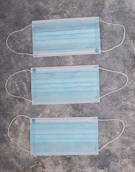 Surgeon masks to protect from Covid-19, worldwide pandemic in 2020 and 2021, blue coloured, empty copy space for text, isolated on a textured background