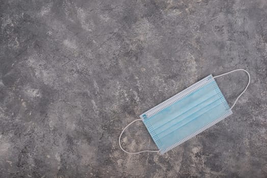 Surgeon masks to protect from Covid-19, worldwide pandemic in 2020 and 2021, blue coloured, empty copy space for text, isolated on a textured background