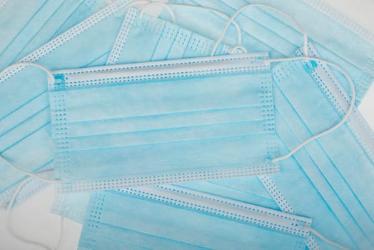 Surgeon masks to protect from Covid-19, worldwide pandemic in 2020 and 2021, blue coloured, empty copy space for text, isolated on a white background