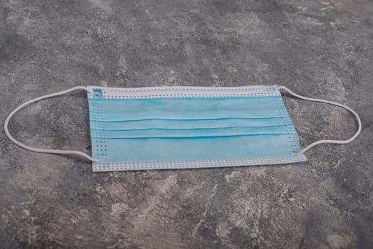 Surgeon masks to protect from Covid-19, worldwide pandemic in 2020 and 2021, blue coloured, empty copy space for text, isolated on a textured background