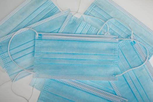 Surgeon masks to protect from Covid-19, worldwide pandemic in 2020 and 2021, blue coloured, empty copy space for text, isolated on a white background