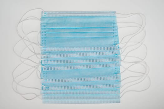 Surgeon masks to protect from Covid-19, worldwide pandemic in 2020 and 2021, blue coloured, empty copy space for text, isolated on a white background