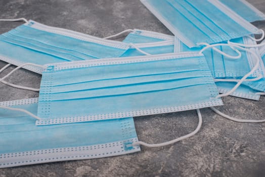 Surgeon masks to protect from Covid-19, worldwide pandemic in 2020 and 2021, blue coloured, empty copy space for text, isolated on a textured background