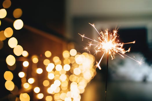 Sparklers on blurred christmas lights. Festive mood. High quality photo