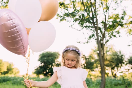 Small shiny girl with pink balloons in the garden. High quality photo
