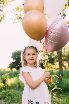 Small shiny girl with pink balloons in the garden. High quality photo