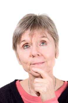 Head portrait of an older woman in front of a white background, looking up, shyly, with her left index finger on her chin.