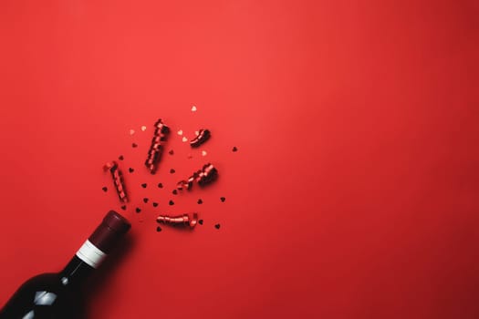 Valentine with bottle of wine, heart glitter and ribbon on red background. High quality photo