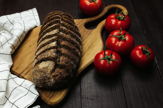 Fresh baked bread and tomatoes on wooden table. High quality photo