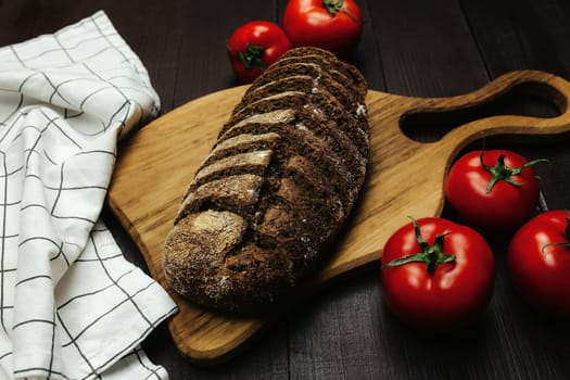 Fresh baked bread and tomatoes on wooden table. High quality photo