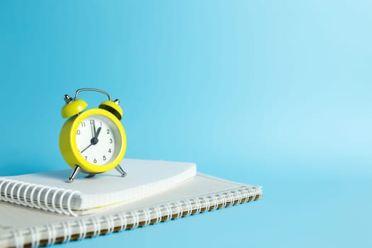 Mechanical alarm clock, notebook on the blue background. High quality photo