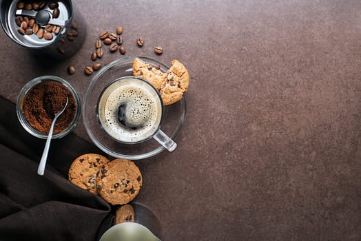 Cup of espresso coffee with coffee beans and coffee grinder on dark table