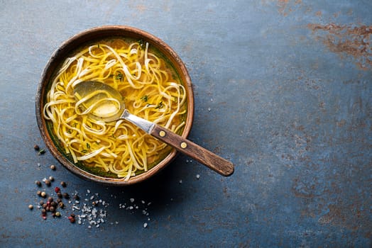 Tasty meat broth soup with herbs and noodles in a bowl closeup