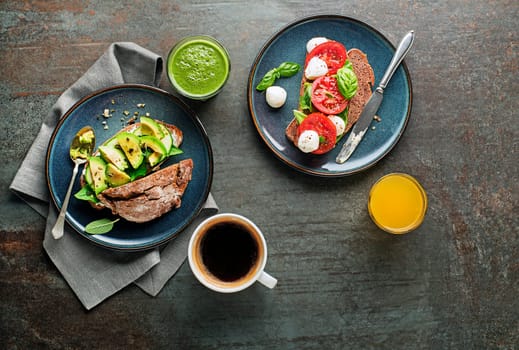 Breakfast served with drinks and vegetarian sandwiches made with avocado, tomato, herbs and cheese. Continental delicious healthy breakfast table