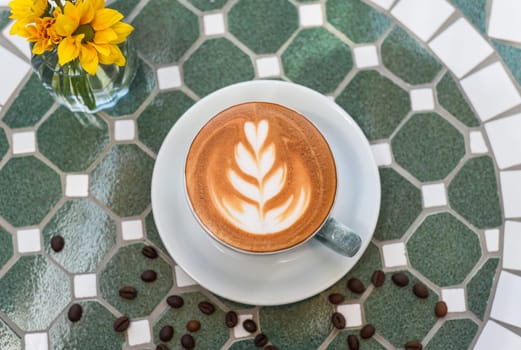 Cup of cappuccino with drawing on light gray background side view