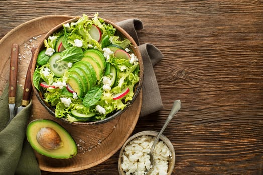 Healthy Green salad with avocado and fresh cheese on wooden table background