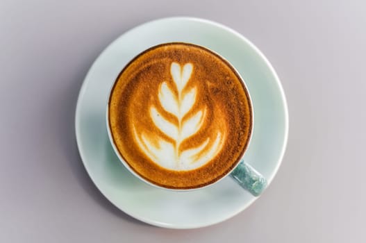 Cup of cappuccino with drawing on light gray background top view