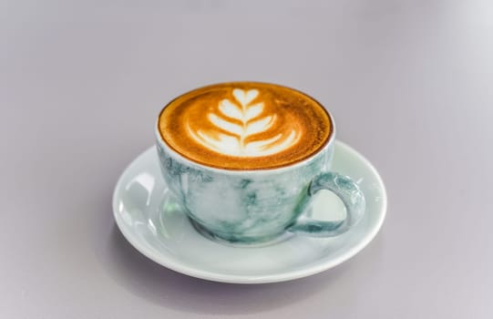 Cup of cappuccino with drawing on light gray background top view