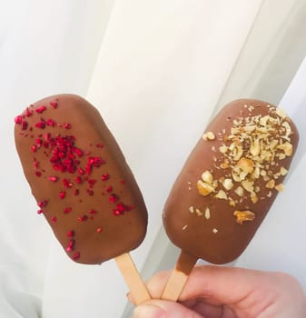 Two Eskimo ice creams on a wooden stick in hand.
