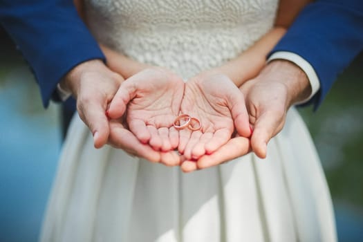 The bride and groom hold rings in their palms. Wedding.