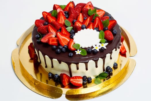 Cake in chocolate glaze and with blueberries and strawberries.