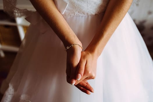The bride crosses her arms on the dress. Excitement in anticipation of the wedding ceremony.