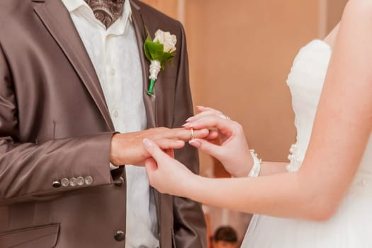The bride puts the groom's ring on her finger. Wedding