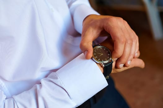 A man in a white shirt looks at his watch.