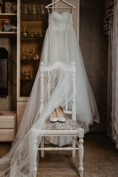 Wedding dress, white shoes on the chair. The bride's clothes.
