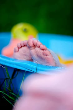 The baby's legs in a plastic bath. The baby is swimming.