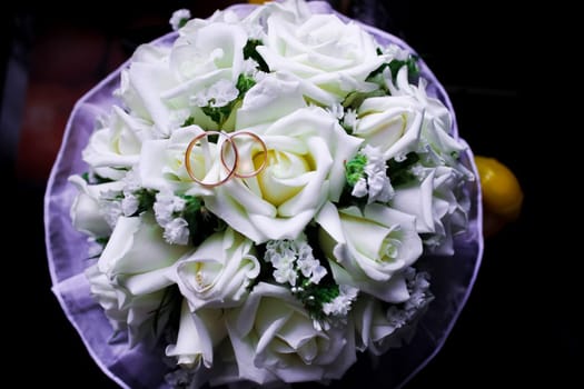 Wedding rings lie on a bouquet of roses. Wedding.