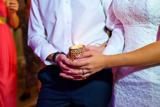 The bride and groom hold the glass together. The newlyweds hold hands.