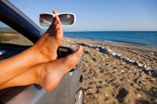Sticking your feet out of the car by the sea. Sunglasses.