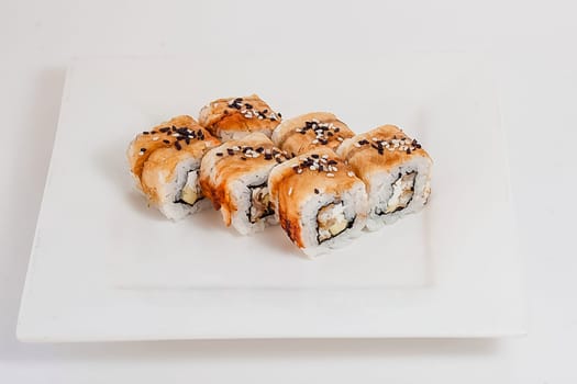 Rolls with red fish and rice on the table in a white plate.