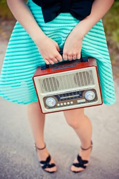 A girl in a dress with a radio in her hand. Retro style.