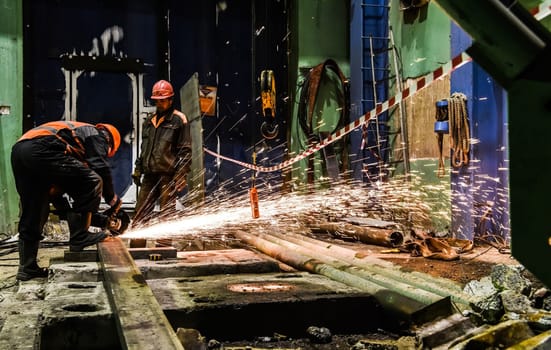 Cutting metal with a corner grind machine. Workers at the factory.