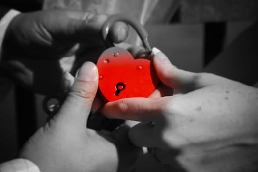 The newlyweds hold a red lock in their hand. Wedding.