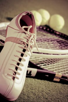 Close_up of a sports shoe with tennis rackets and tennis balls
