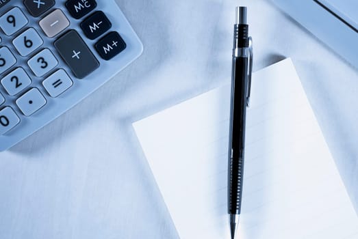Close_up of a calculator and a ballpoint pen with a paper
