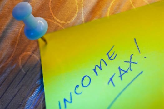 Close_up of text Income Tax written on an adhesive note